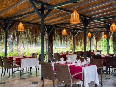 Comedor abierto con mesas preparadas y lámparas colgantes en un ambiente tropical.