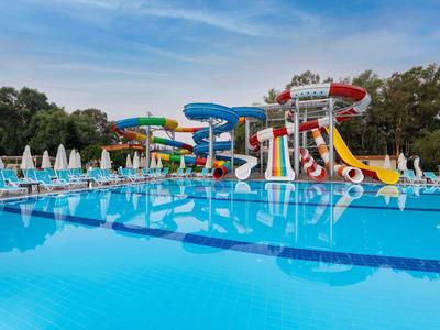 Una gran piscina con toboganes acuáticos y tumbonas bajo un cielo azul.