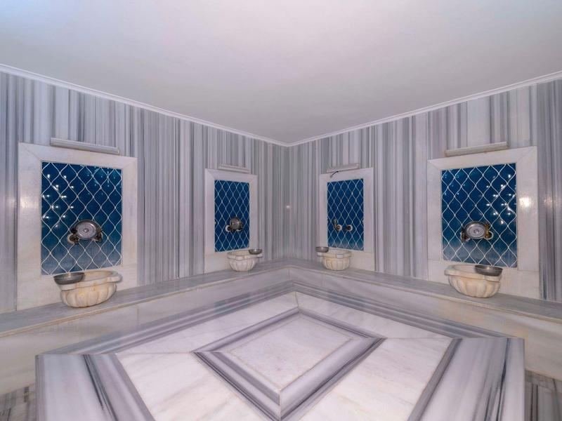 Elegante hamam turco con mármol y rejas azules, limpio y bien cuidado.