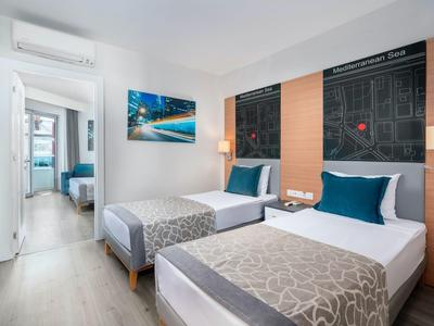 Camera d'hotel moderna con due letti singoli, accenti blu e decorazione con mappa della città.