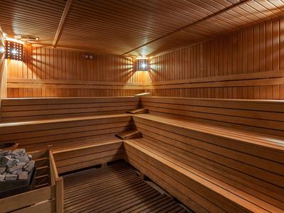 Sauna in legno con panche a più livelli e pietre per infusione nell'angolo