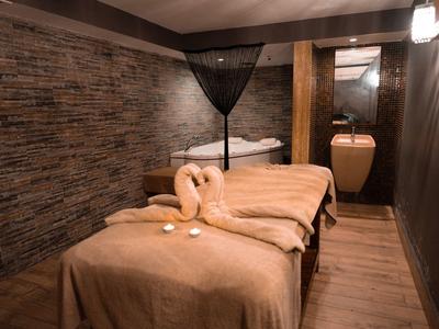 Stanza spa tranquilla con due lettini da massaggio, decorazioni e interno caldo in legno e pietra.