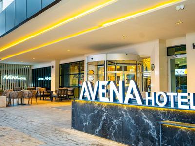 Entrée d'hôtel avec enseigne AVENA illuminée et espace extérieur de détente la nuit