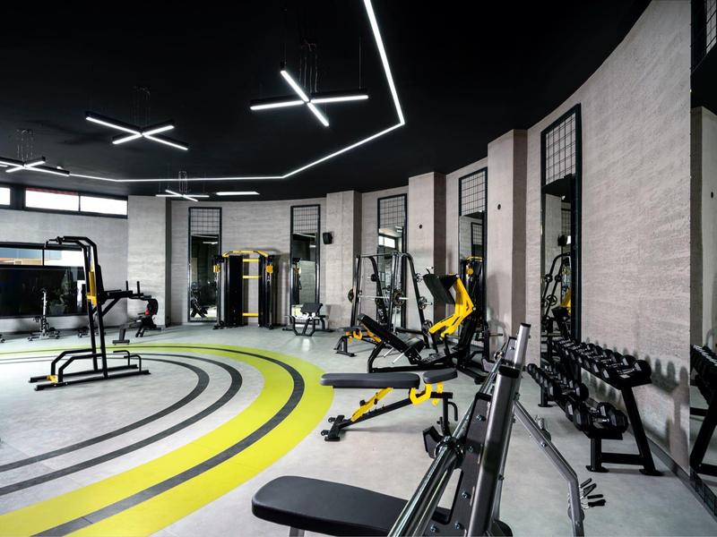 Palestra moderna con varie attrezzature e strisce gialle sul pavimento.
