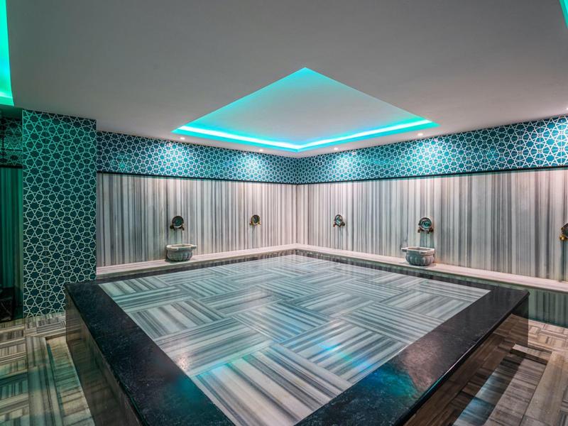 Piscina interna moderna con motivi geometrici delle piastrelle e illuminazione blu sul soffitto