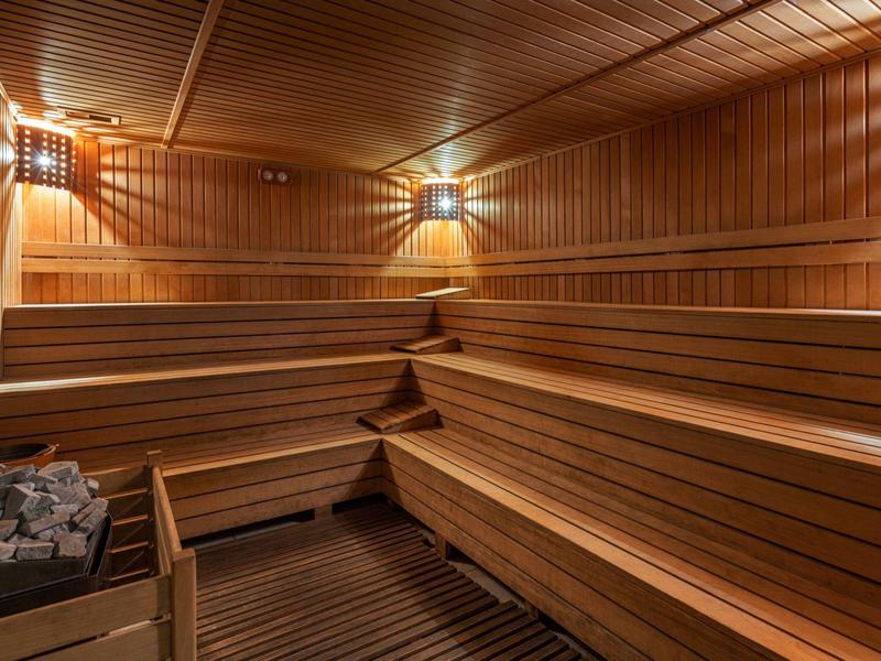 Sauna in legno con panche a più livelli e pietre per infusione nell'angolo