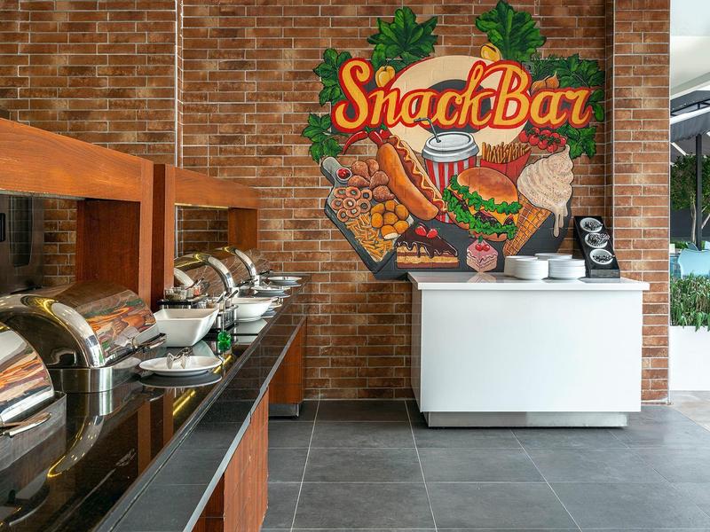 Area snack bar moderna con buffet e decorazioni murali colorate in uno spazio aperto.