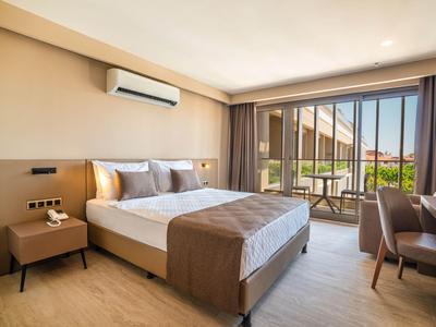 Modernes Hotelzimmer mit Doppelbett, Schreibtisch, Stühlen und Blick auf eine Terrasse.