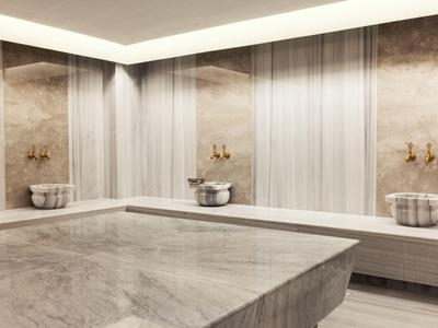 Helles, luxuriöses Hamam mit marmorverkleideten Wänden und zentraler Marmorplatte.