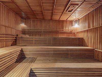 Innenansicht einer hölzernen Sauna mit mehrstufigen Sitzbänken und warmem Licht.