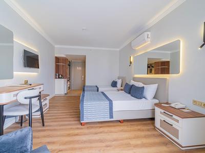 Modernes Hotelzimmer mit Doppelbett, Schreibtisch, Stuhl und Wandspiegel mit Beleuchtung.