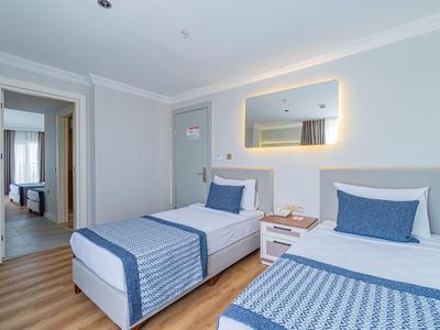 Helles Hotelzimmer mit zwei Einzelbetten, blauen und weißen Bettdecken und Holzboden.