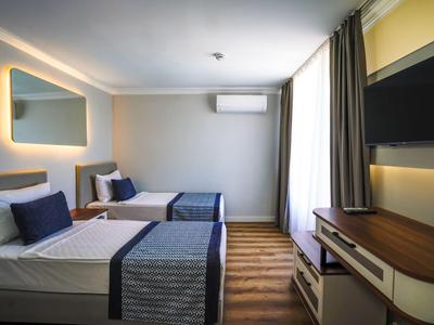 Modern eingerichtetes Hotelzimmer mit zwei Einzelbetten, Holzboden und Flachbildfernseher.