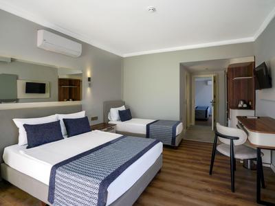 Moderner Hotelraum mit zwei komfortablen Betten, Schreibtisch und Fernseher in neutralen Farben.