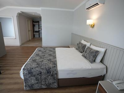 Modern eingerichtetes Hotelzimmer mit Doppelbett, Nackenstützkissen und Holzboden.