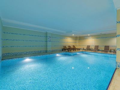 Innenpool mit blauen Fliesen und Liegestühlen in einem Hotelzimmer.