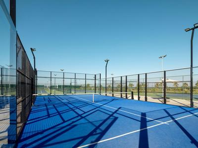 Blauer Paddle-Tennisplatz mit Umzäunung und klar blauem Himmel im Hintergrund