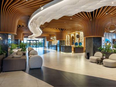 Moderne Hotellobby mit geschwungenen Holzelementen und stilvollen Sitzbereichen in hellem Ambiente