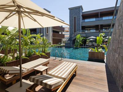 Moderní bazénová plocha s lehátky a slunečníkem v hotelu.