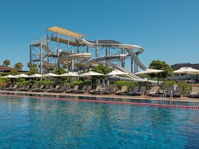 Vodní park s velkými skluzavkami a lehátky u bazénu za jasné oblohy.