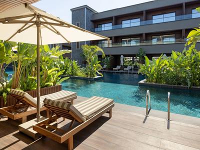 Venkovní bazén s lehátky a slunečníkem v moderním hotelu.