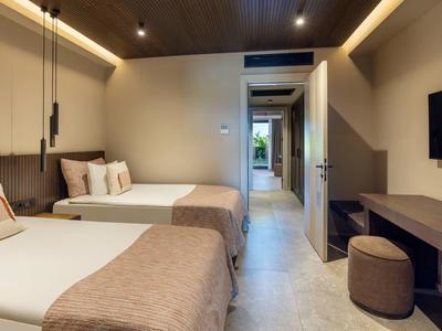 Moderní hotelový pokoj se dvěma postelemi, dřevěným nábytkem a TV s plochou obrazovkou.