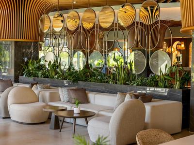 Moderne Lounge mit runden Sesseln, Holzdeckenakzenten, Spiegelwand und grünen Pflanzen.