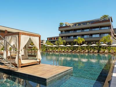 Luxusní bazén s deštníky a krytým lehátkem na dřevěné plošině