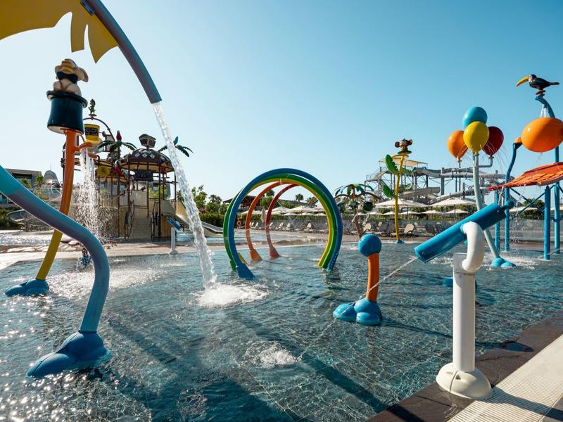 Barevné vodní hřiště se skluzavkami a stříkacími objekty pod jasnou oblohou