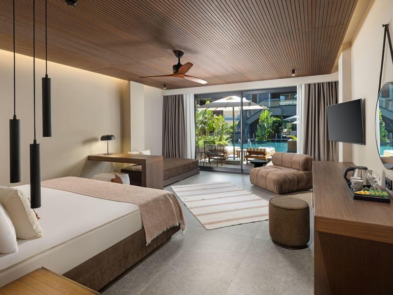 Moderní hotelový pokoj se dvěma postelemi, balkónem a výhledem na zahradu a bazén.