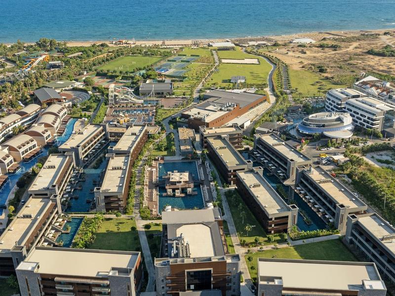 Letecký pohled na moderní pobřežní resort s několika budovami a výhledem na moře.