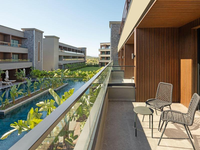 Balkon se dvěma židlemi s výhledem na hotelový bazén a zahradu.