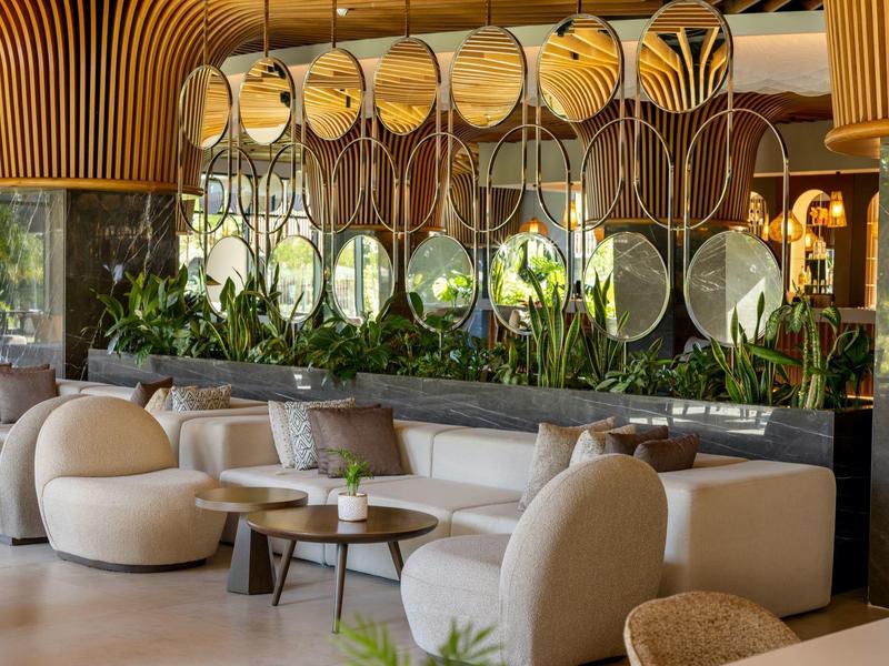 Moderní hotelová lounge s pohodlnými křesly a zrcadlovou nástěnnou dekorací.