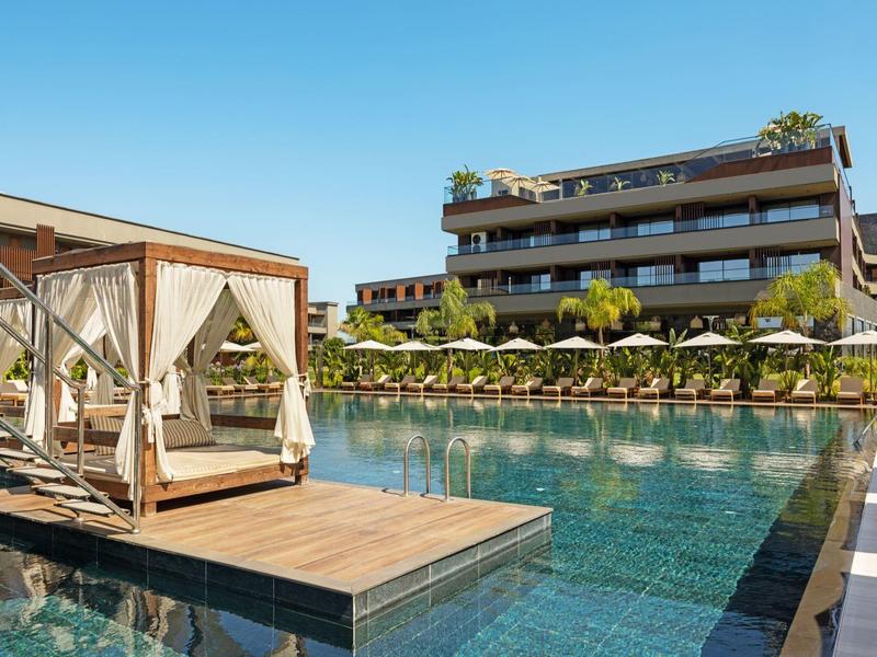 Luxusní bazén s deštníky a krytým lehátkem na dřevěné plošině