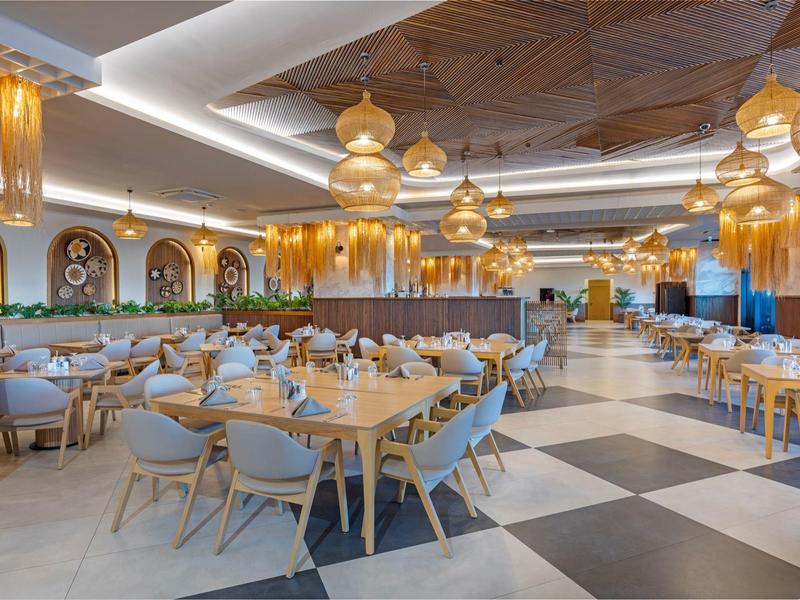 Elegantní hotelová restaurace s moderním dřevěným nábytkem, modrými židlemi a teplým osvětlením.