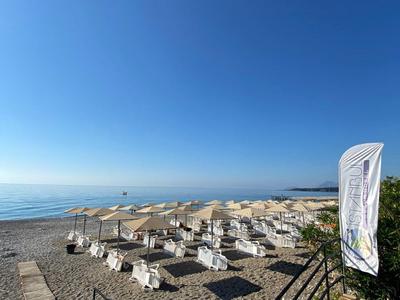 Spiaggia con ombrelloni, sdraio e cielo azzurro limpido vicino al mare.