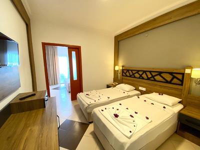 Camera d'hotel moderna con due letti singoli, mobili in legno e accesso al balcone.