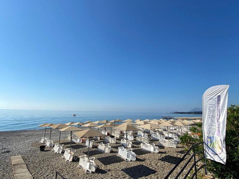 Spiaggia con ombrelloni, sdraio e cielo azzurro limpido vicino al mare.