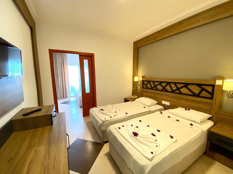 Camera d'hotel moderna con due letti singoli, mobili in legno e accesso al balcone.