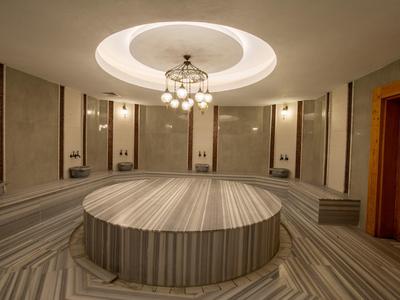 Großer runder Marmor-Tisch in luxuriösem Hamam mit warmem Licht und Holzrahmen.