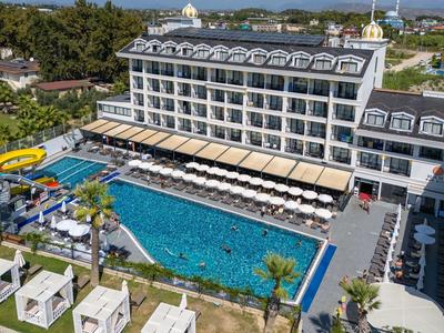 Großes Hotel mit mehrstöckigem Gebäude, Pool mit Wasserrutsche und Liegestühlen im Außenbereich.