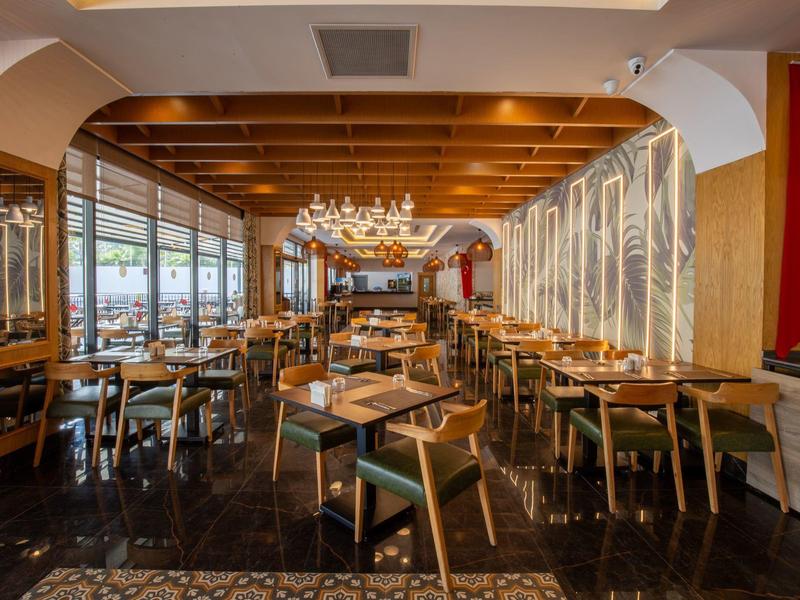 Restaurant élégant avec mobilier en bois, lustres et drapeau turc au mur.