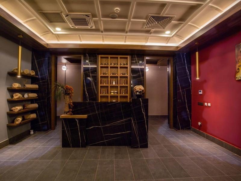 Espace de réception d'hôtel moderne avec comptoir en marbre foncé et éclairage élégant.