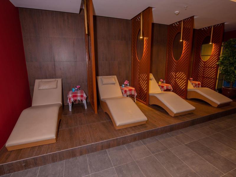 Quatre chaises longues avec cloisons en bois et murs rouges dans un espace spa.