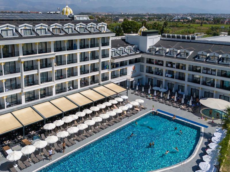 Grand hôtel avec piscine et de nombreux clients sur des transats extérieurs.