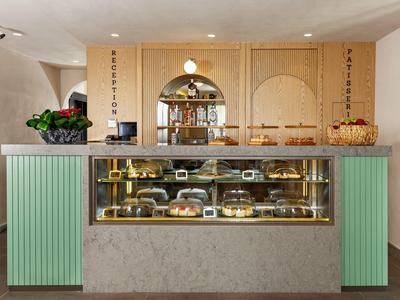 Kuchenladen mit gläserner Theke, grünen Seitenverkleidungen und Holzdekor an der Wand.