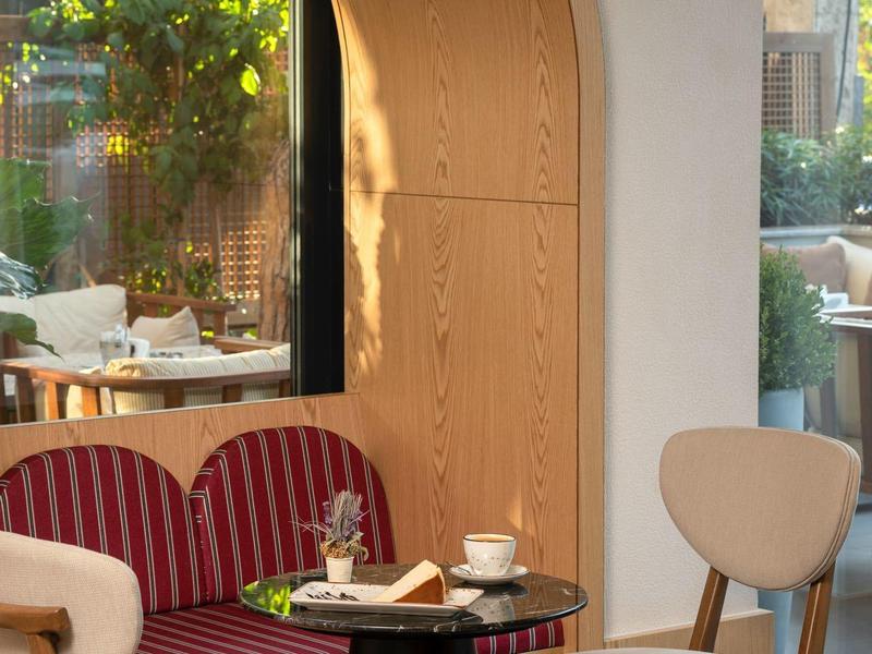 Gemütliche Ecke mit rotem, gestreiftem Sofa, zwei Holztstühlen und einem runden schwarzen Tisch.