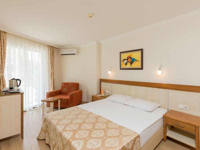 Bright hotel room with double bed, armchair, and TV near the window.