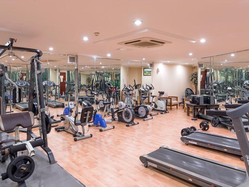 A modern gym with various exercise machines and mirrored walls in a hotel.