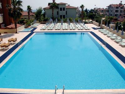 Grande piscine rectangulaire avec chaises longues et parasols dans un hôtel.